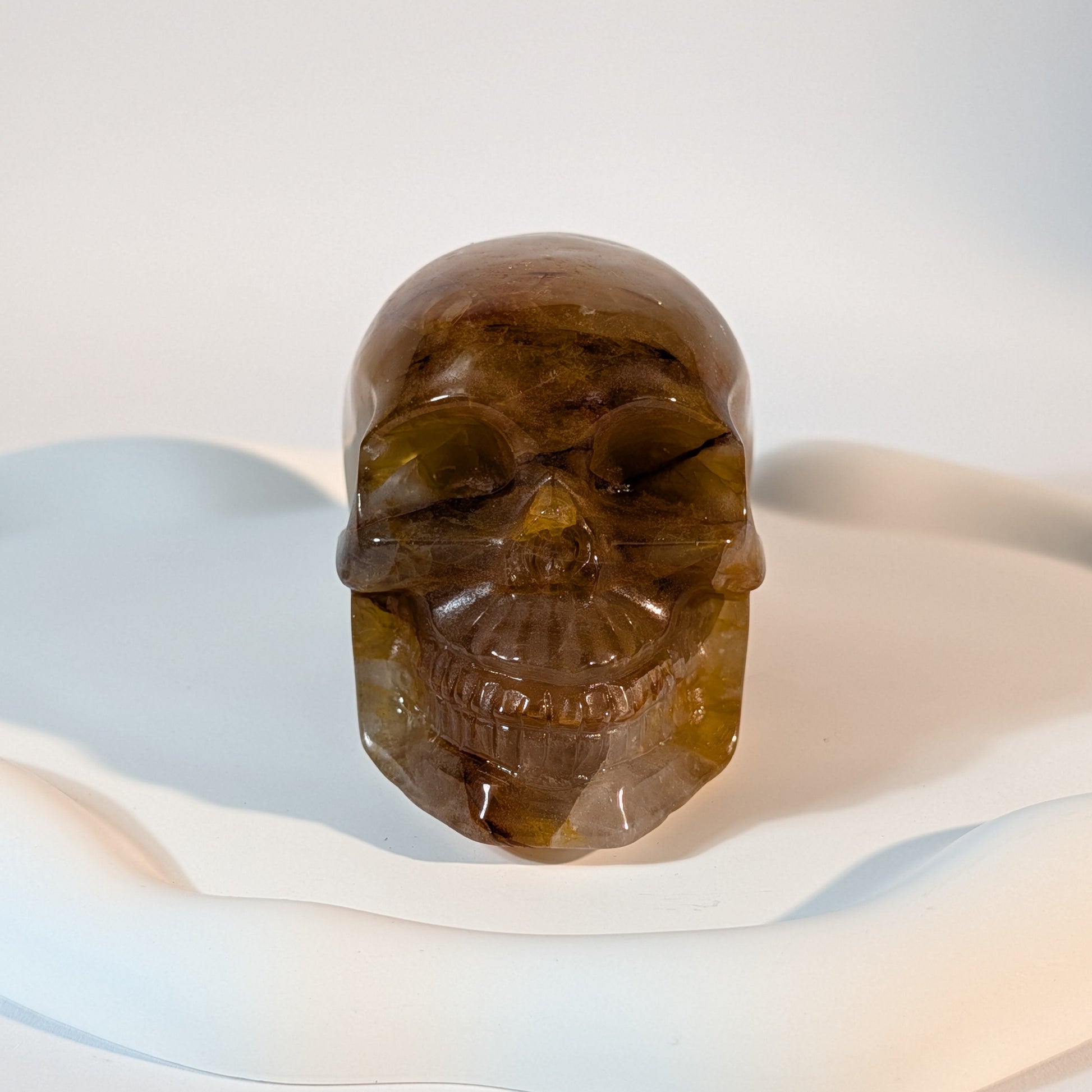 Massiver, bernsteinfarbener Kristallschädel Muirne aus Quarz mit tiefen, dunklen Rissen und rostigen Eiseneinschlüssen.