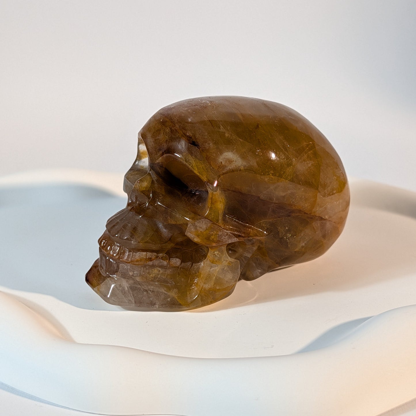 Massiver, bernsteinfarbener Kristallschädel Muirne aus Quarz mit tiefen, dunklen Rissen und rostigen Eiseneinschlüssen.