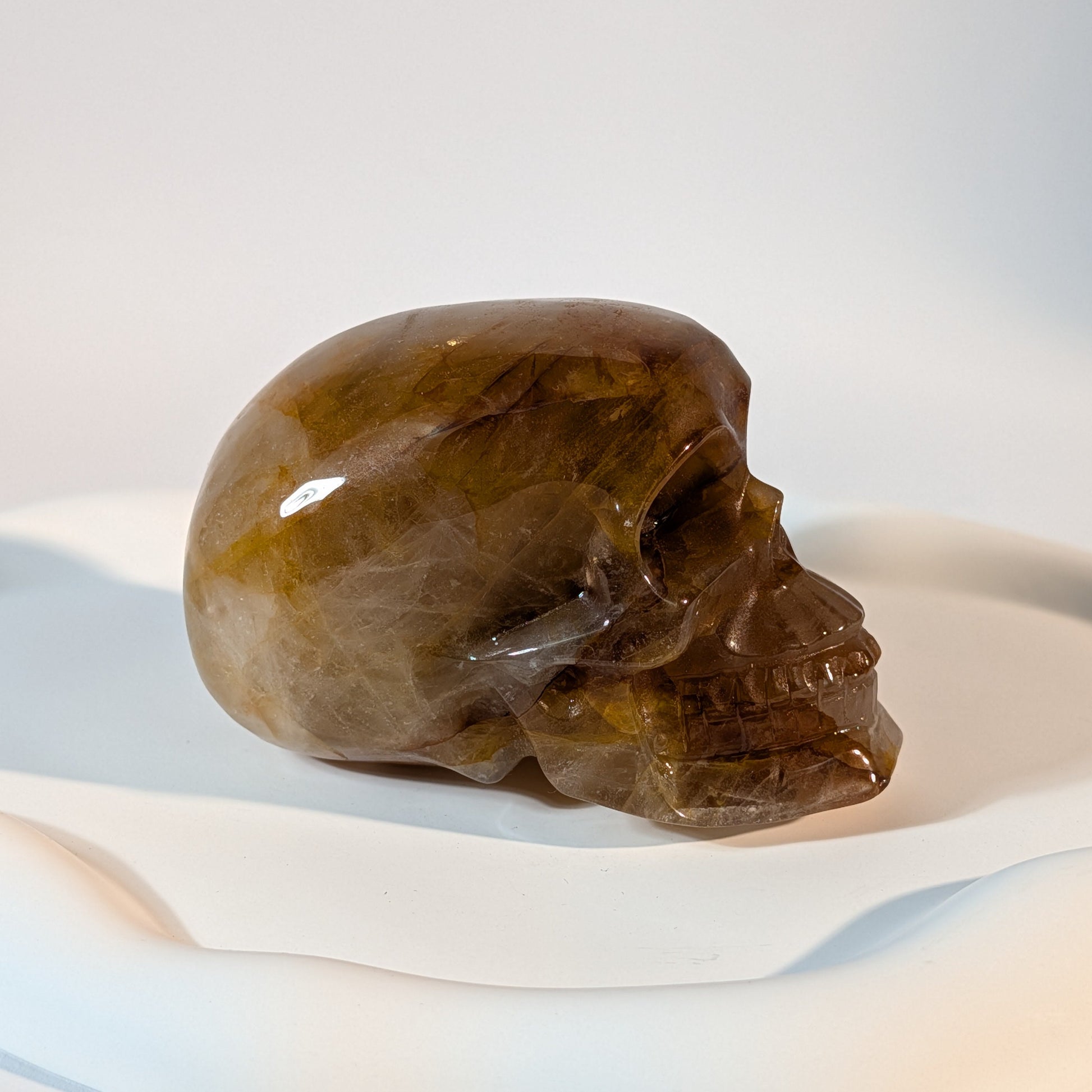 Massiver, bernsteinfarbener Kristallschädel Muirne aus Quarz mit tiefen, dunklen Rissen und rostigen Eiseneinschlüssen.