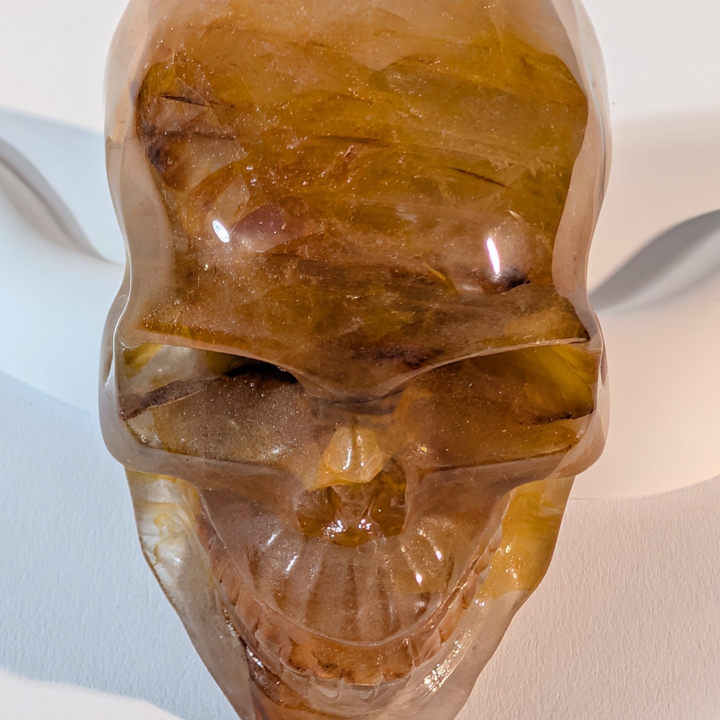 Massiver, bernsteinfarbener Kristallschädel Muirne aus Quarz mit tiefen, dunklen Rissen und rostigen Eiseneinschlüssen.