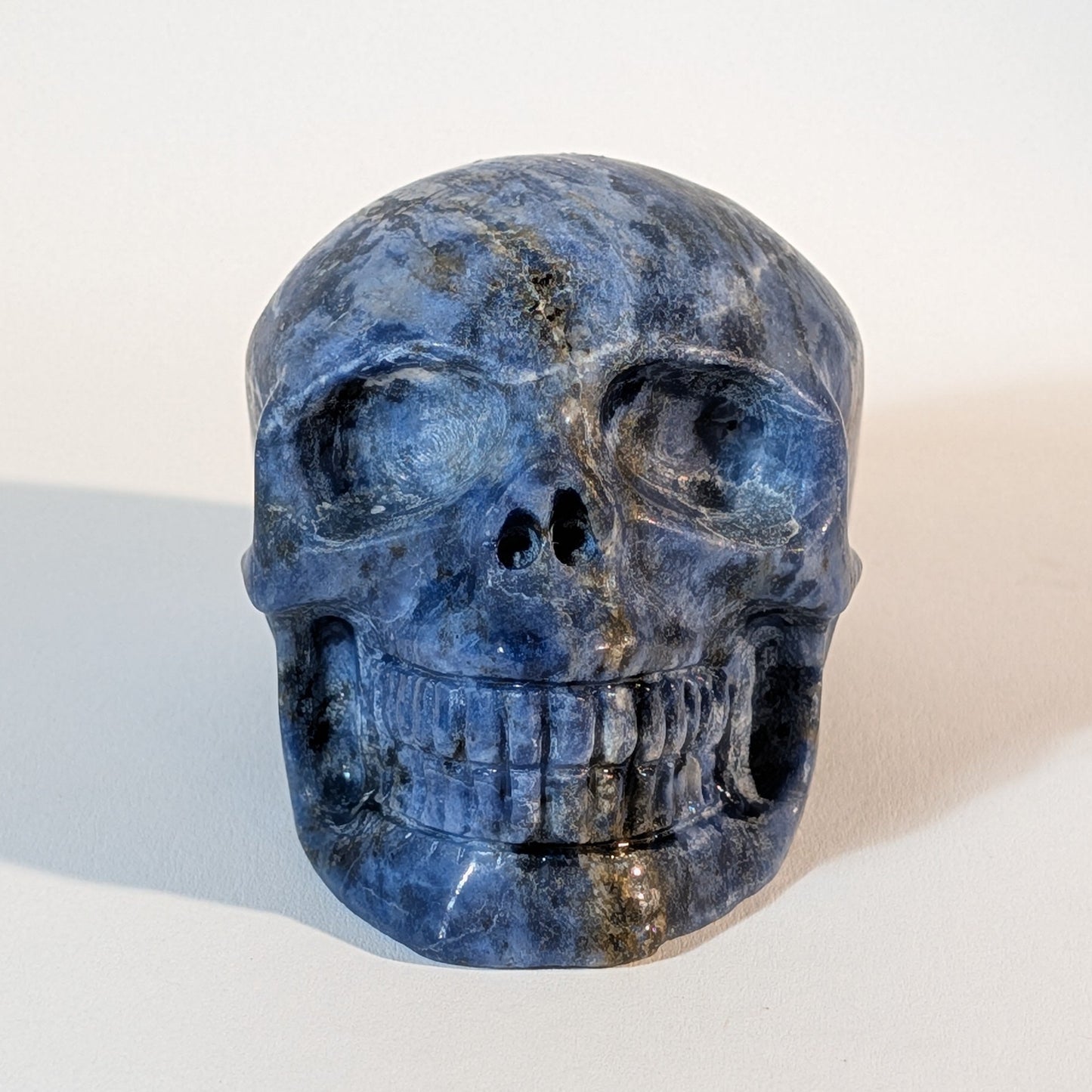 Mittelgroßer Kristallschädel Iawar aus tiefblauem Sodalith, 418 Gramm schwer, durchzogen mit natürlichen Calcit-Einschlüssen für Intuition und Klarheit.