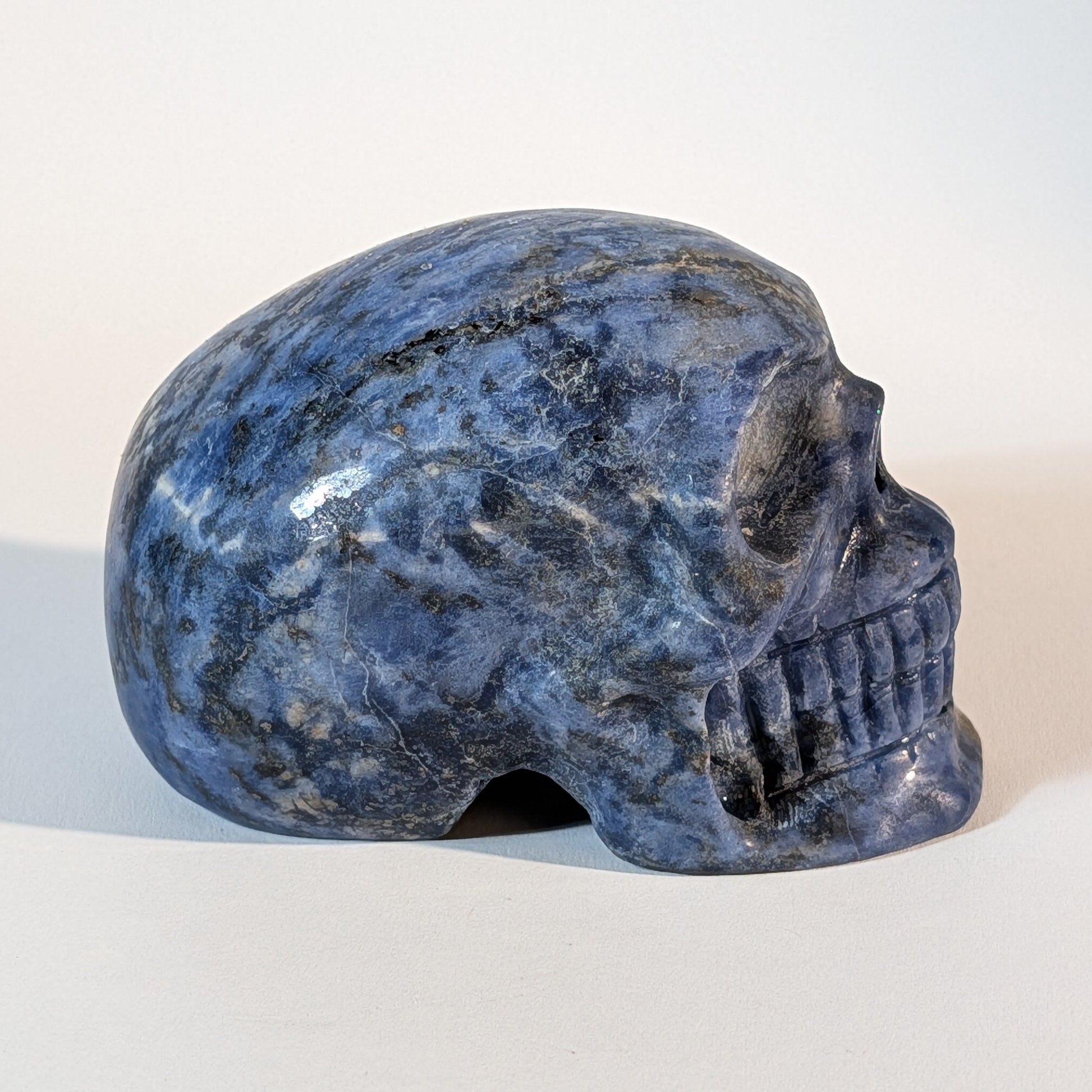 Mittelgroßer Kristallschädel Iawar aus tiefblauem Sodalith, 418 Gramm schwer, durchzogen mit natürlichen Calcit-Einschlüssen für Intuition und Klarheit.