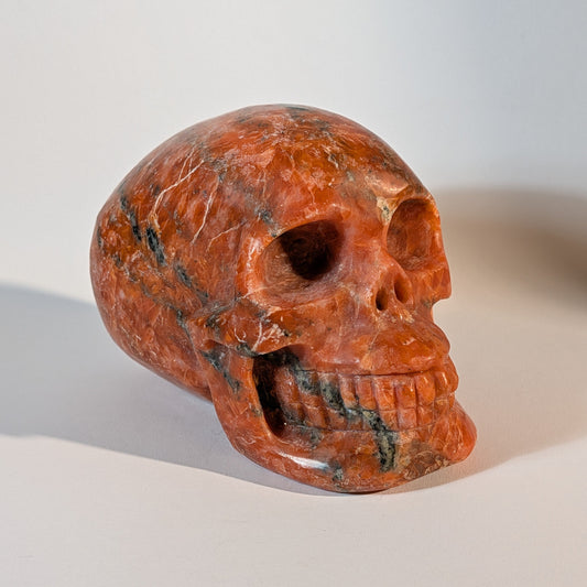 Mittelgroßer, handgeschnitzter Kristallschädel Istemo aus orange-rotem Sonnenstein (Oligoklas), 935 Gramm schwer, für Lebensfreude und Optimismus.