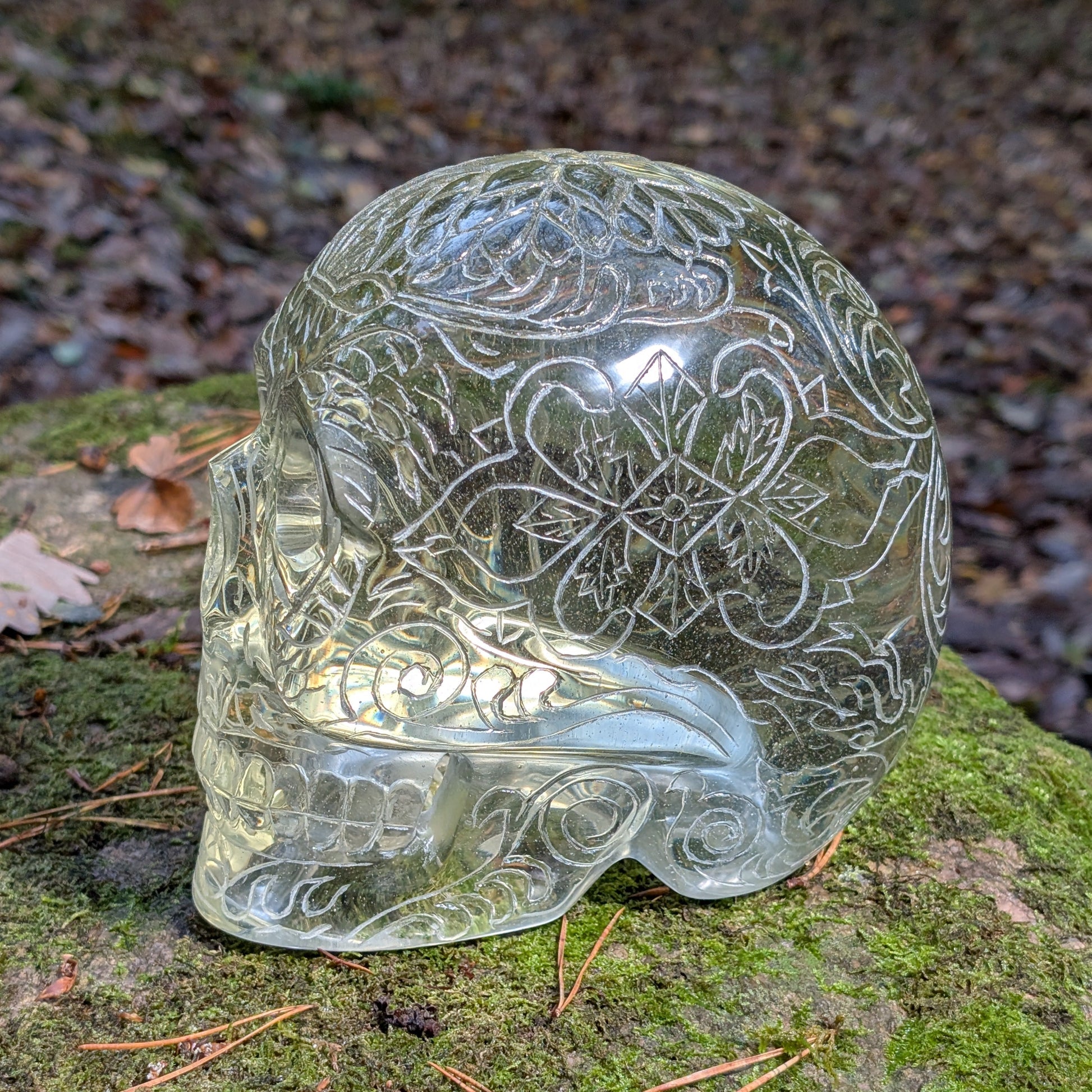 Monumentaler 6.4kg Kristallschädel "Hekate" aus gelbem Obsidian mit vollflächiger Handgravur, auf Moos im Wald liegend.