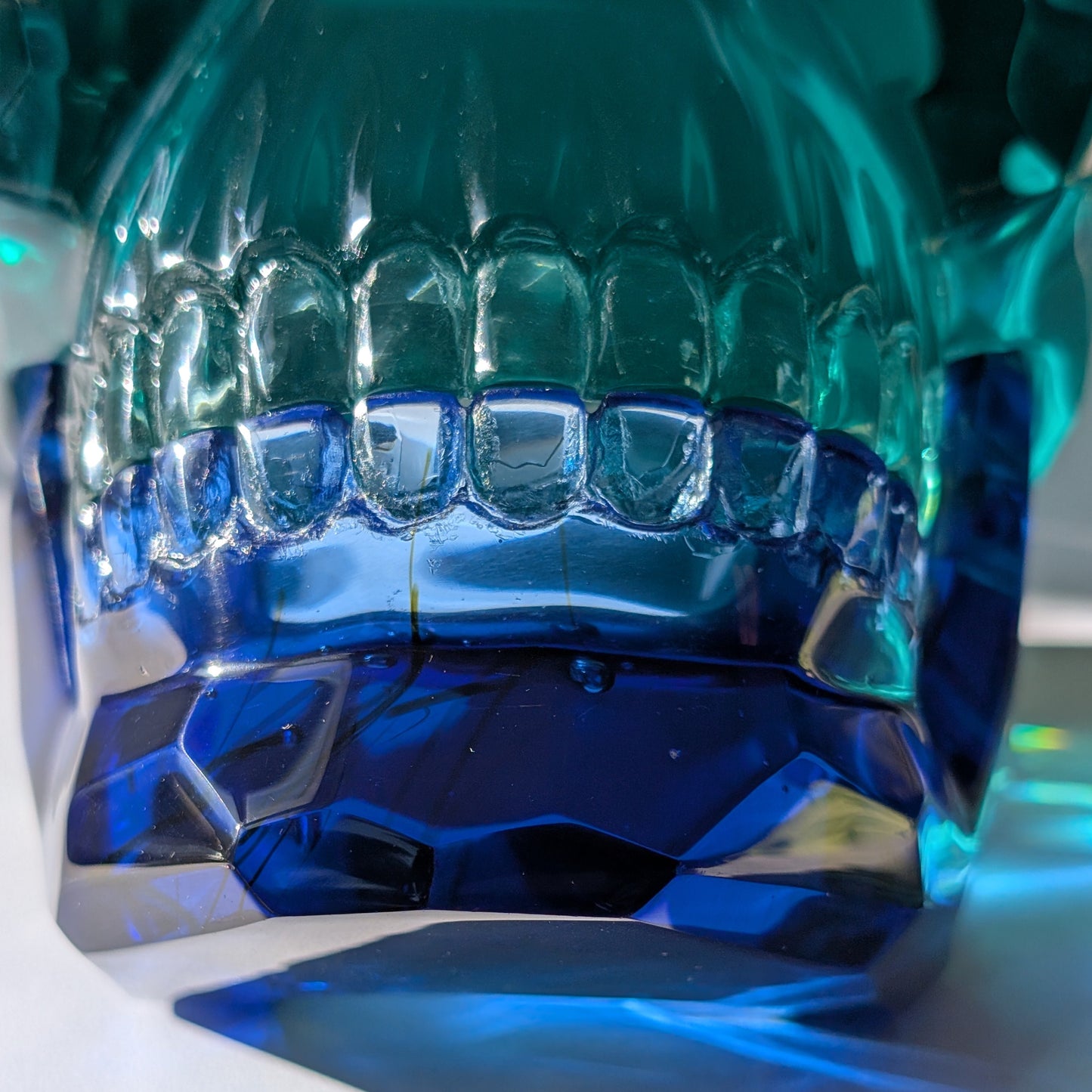 Monumentaler Kristallschädel (7.5kg) aus facettiertem blaugrünem Glas mit beweglichem Unterkiefer im Lichtspiel.