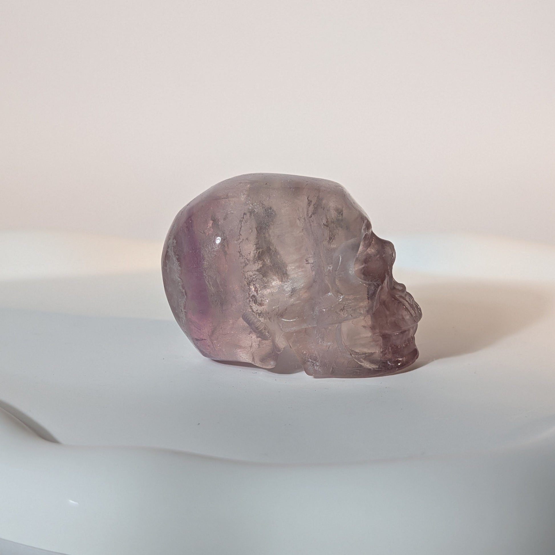 Kompakter Kristallschädel Vandarr aus durchscheinendem, violettem Fluorit mit rauer, körniger Lichtwirkung und tiefen Schatten.