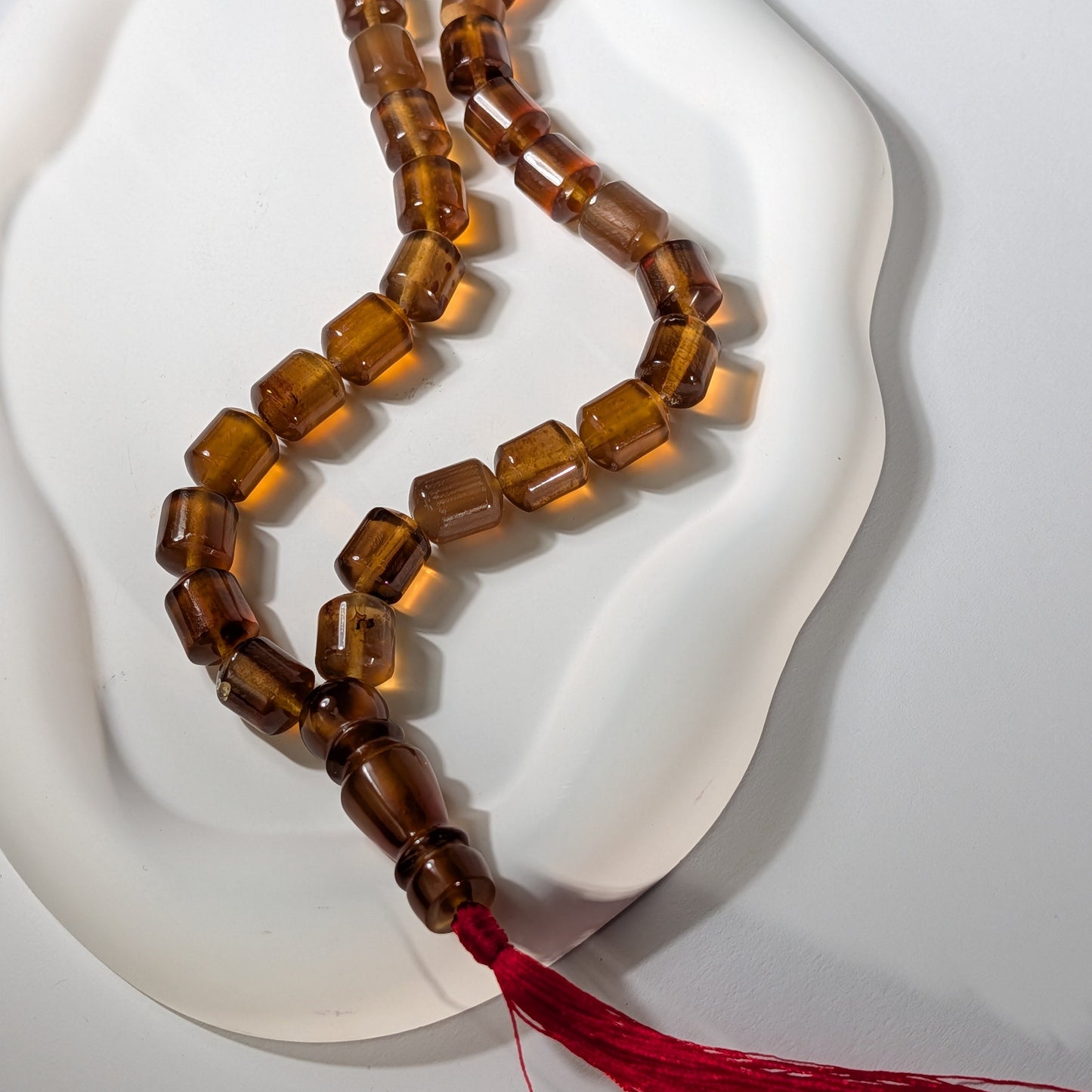 Exklusive, handgefertigte Gebetskette (Mala/Tasbih) aus honigfarbenem Bernstein in Walzenform mit roter Quaste, 50g für Meditation und Schutz - Temple of Desire