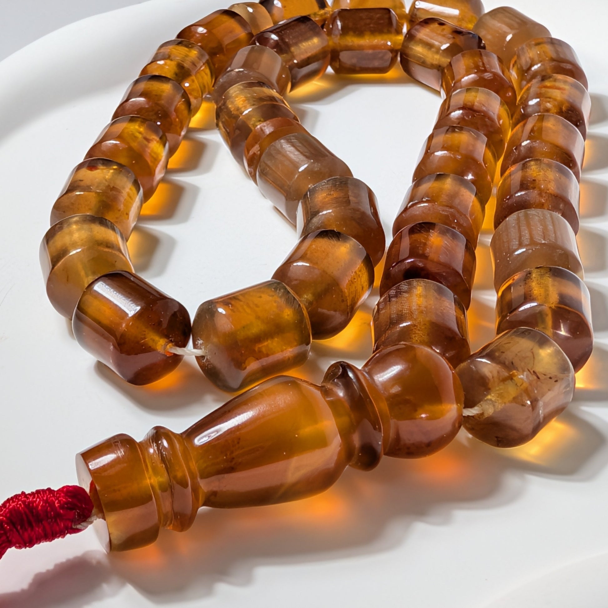 Exklusive, handgefertigte Gebetskette (Mala/Tasbih) aus honigfarbenem Bernstein in Walzenform mit roter Quaste, 50g für Meditation und Schutz - Temple of Desire