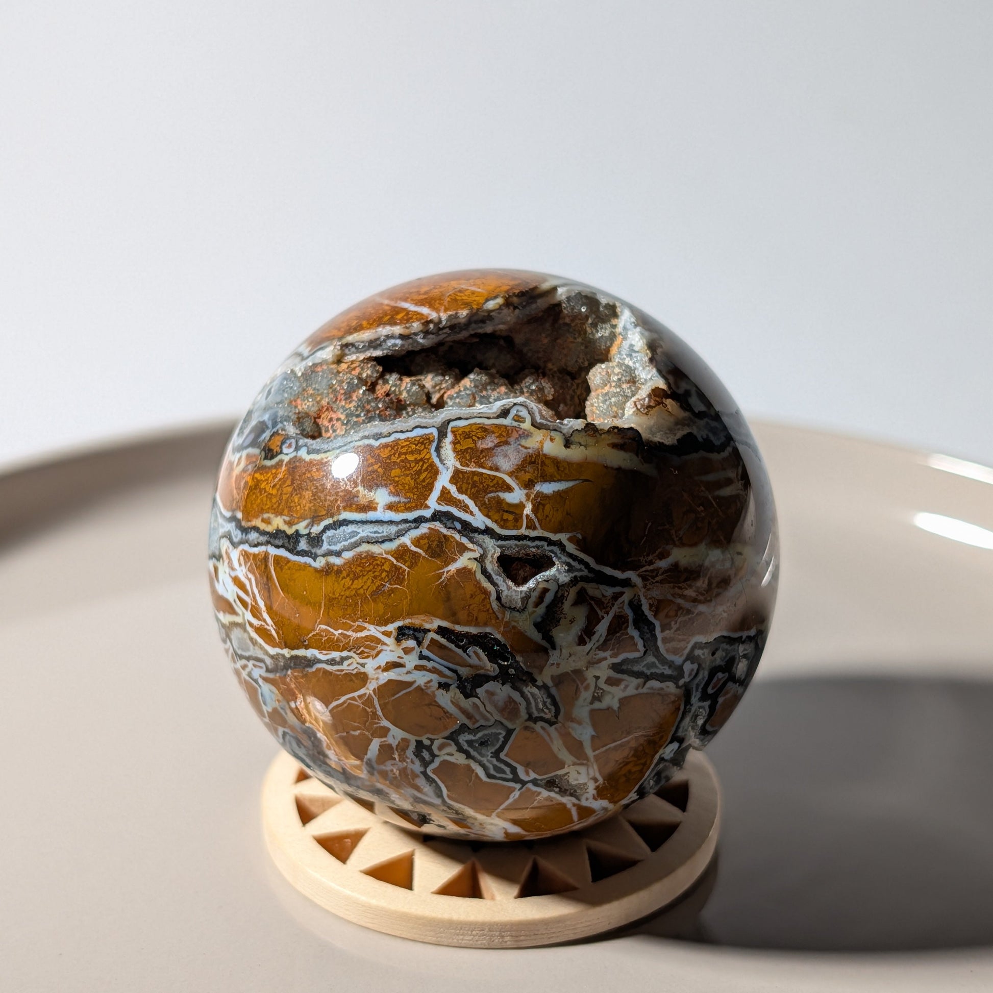 Polierte Drusenachat Kugel in Nahaufnahme mit offener Kristall-Geode und goldgelber Bänderung