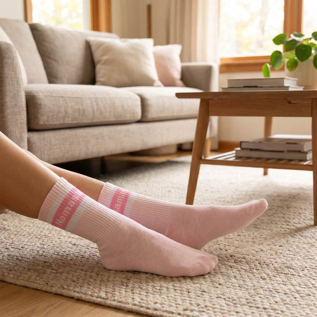 Rosa Namasté-Socken an den Füßen auf dem Teppich