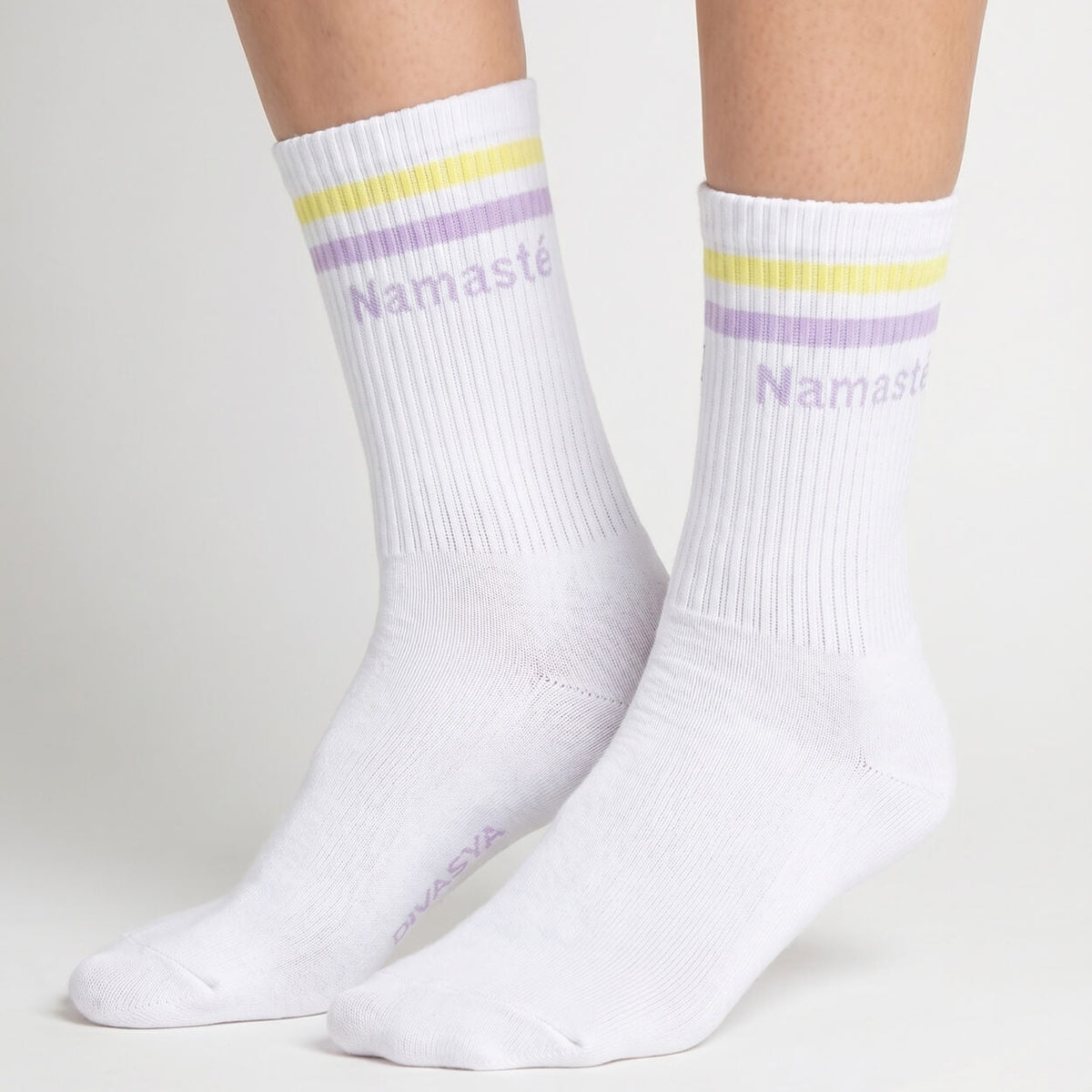 Weiße Yoga-Socken mit Namasté-Schriftzug und gelb-lila Streifen an den Füßen