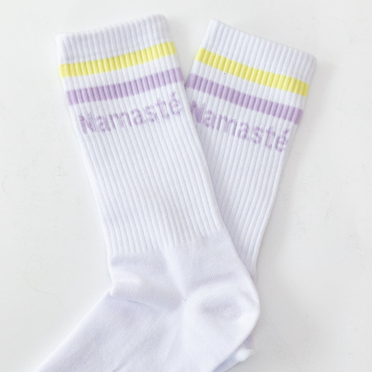 Paar weiße Namasté-Socken mit gelb-lila Streifen liegend