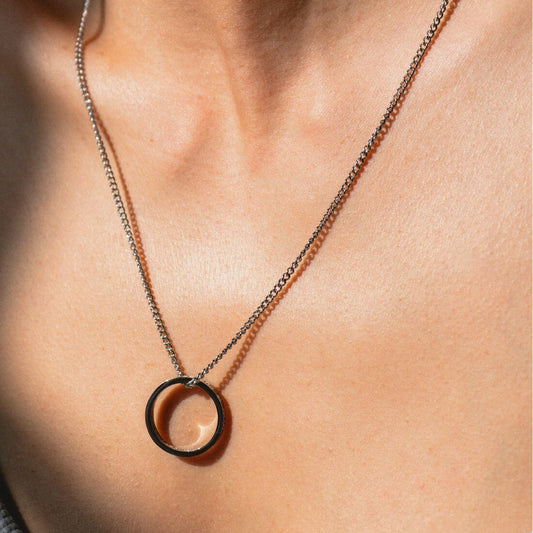 Silberne Ringkette getragen über schlichtem Oberteil
