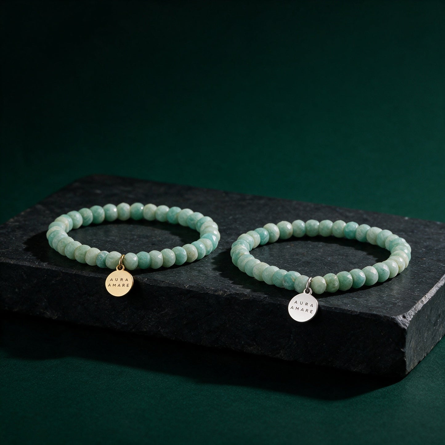Amazonit Armbänder in Gold und Silber von AURA AMARE auf dunklem smaragdgrünem Hintergrund