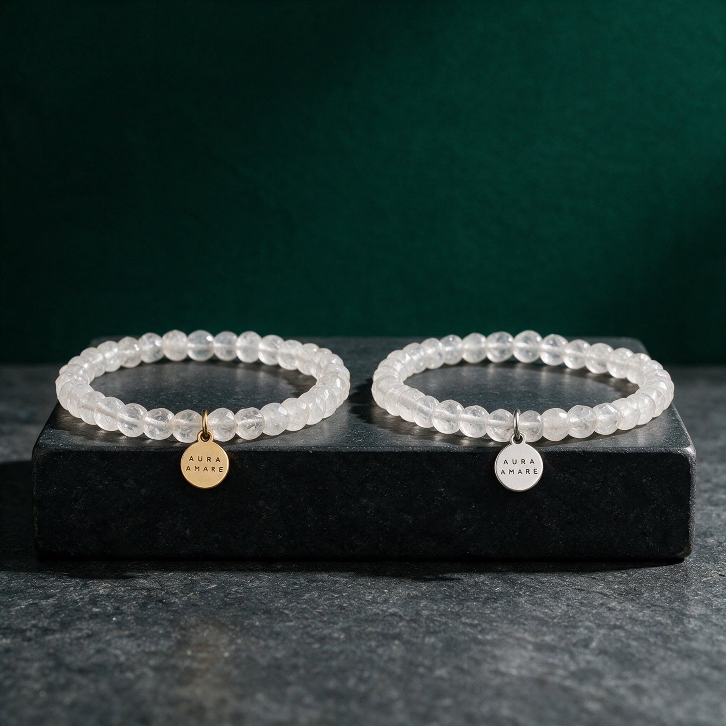 Bergkristall Armband in Gold und Silber von AURA AMARE vor tiefem Smaragdgrün