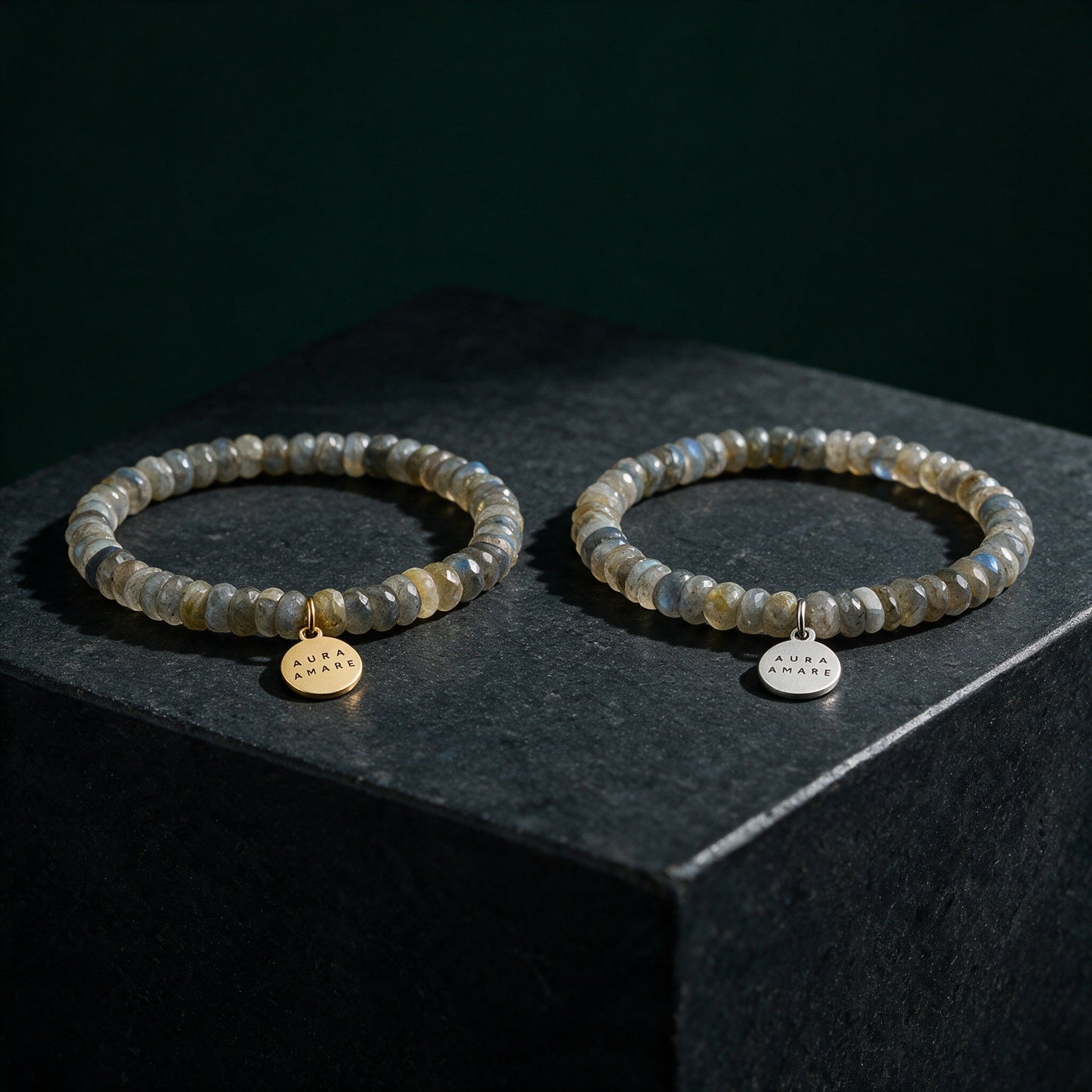 Labradorit Armband in Gold und Silber von AURA AMARE vor tiefem Smaragdgrün
