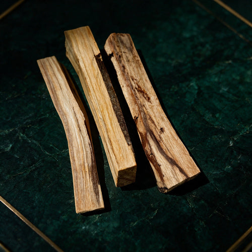 Drei Palo-Santo-Sticks von AURA AMARE vor tiefem Smaragdgrün