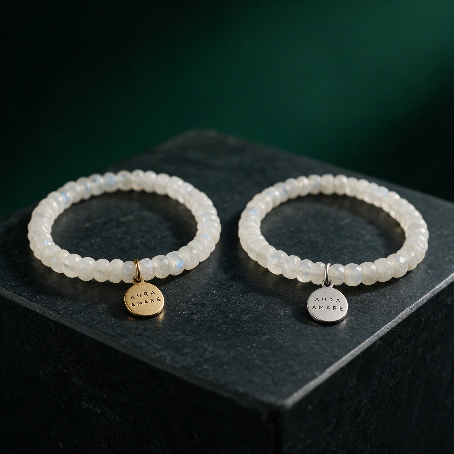 Regenbogen-Mondstein Armband in Gold und Silber von AURA AMARE vor tiefem Smaragdgrün