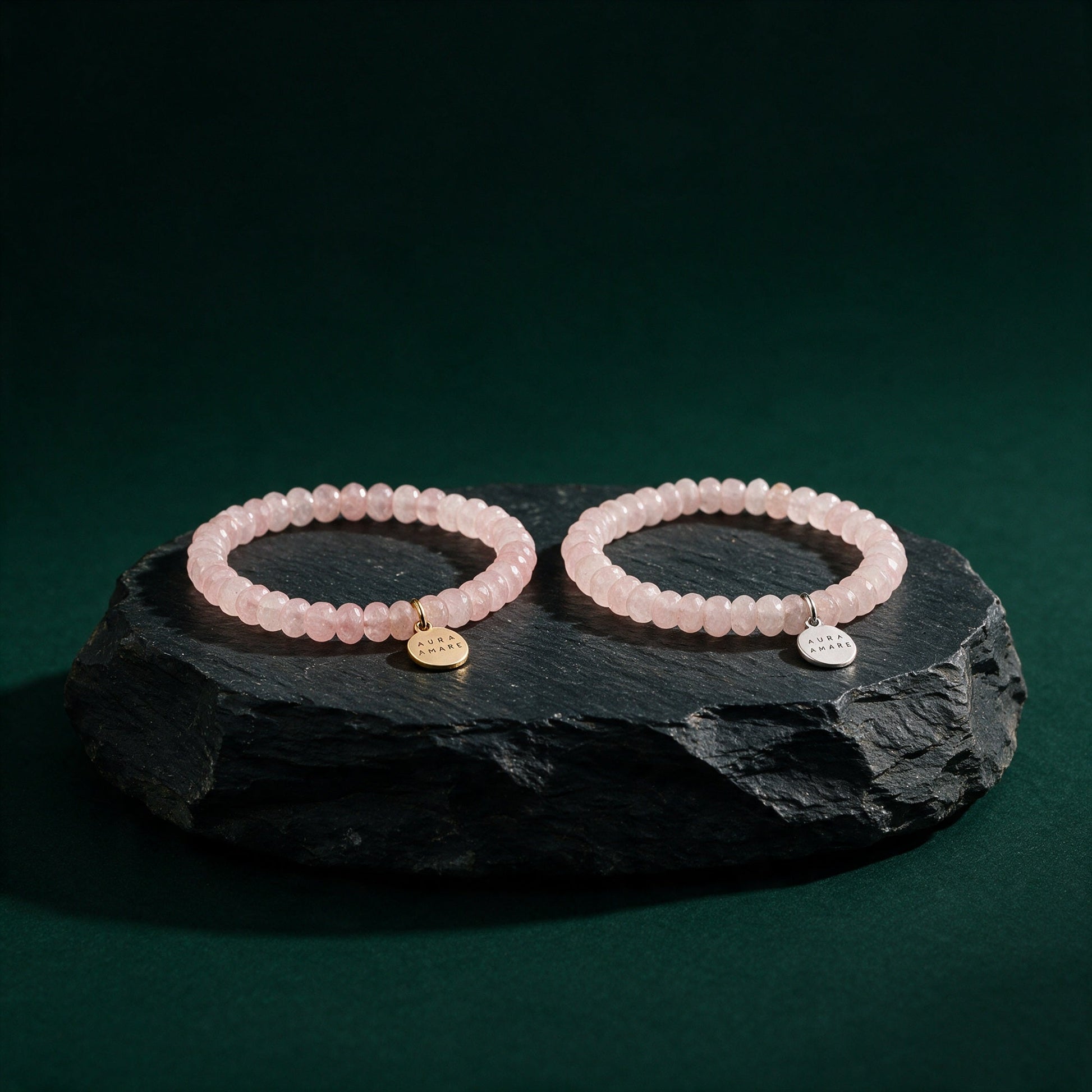 Rosenquarz Armband in Gold und Silber von AURA AMARE vor tiefem Smaragdgrün