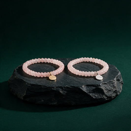 Rosenquarz Armband in Gold und Silber von AURA AMARE vor tiefem Smaragdgrün
