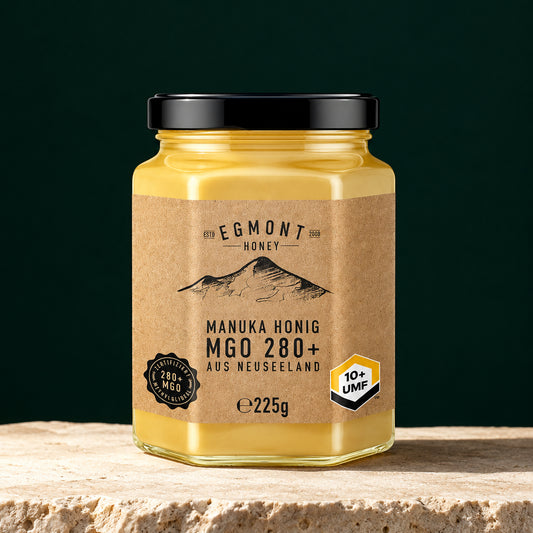 Egmont Honey MGO 280+ im Sechskantglas auf hellem Stein vor dunkelgrünem Hintergrund