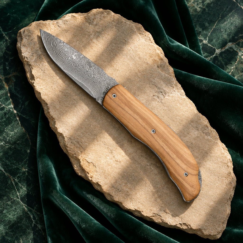 Damast-Taschenmesser 70 mm mit Olivenholzgriff auf hellem Stein und grünem Samt