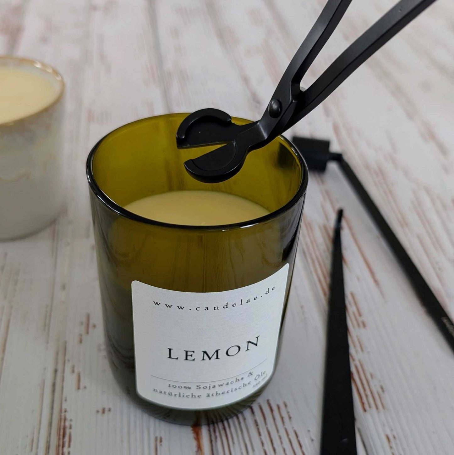 Dochtschere kürzt den Docht einer Candelae Lemon Duftkerze