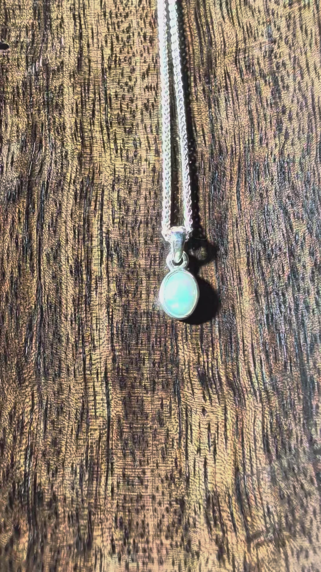 Polierter ovaler Opal Anhänger mit leuchtendem Farbspiel in einer schlichten 925er Silberfassung an einer Silberkette, energetisch aufgeladen von Temple of Desire