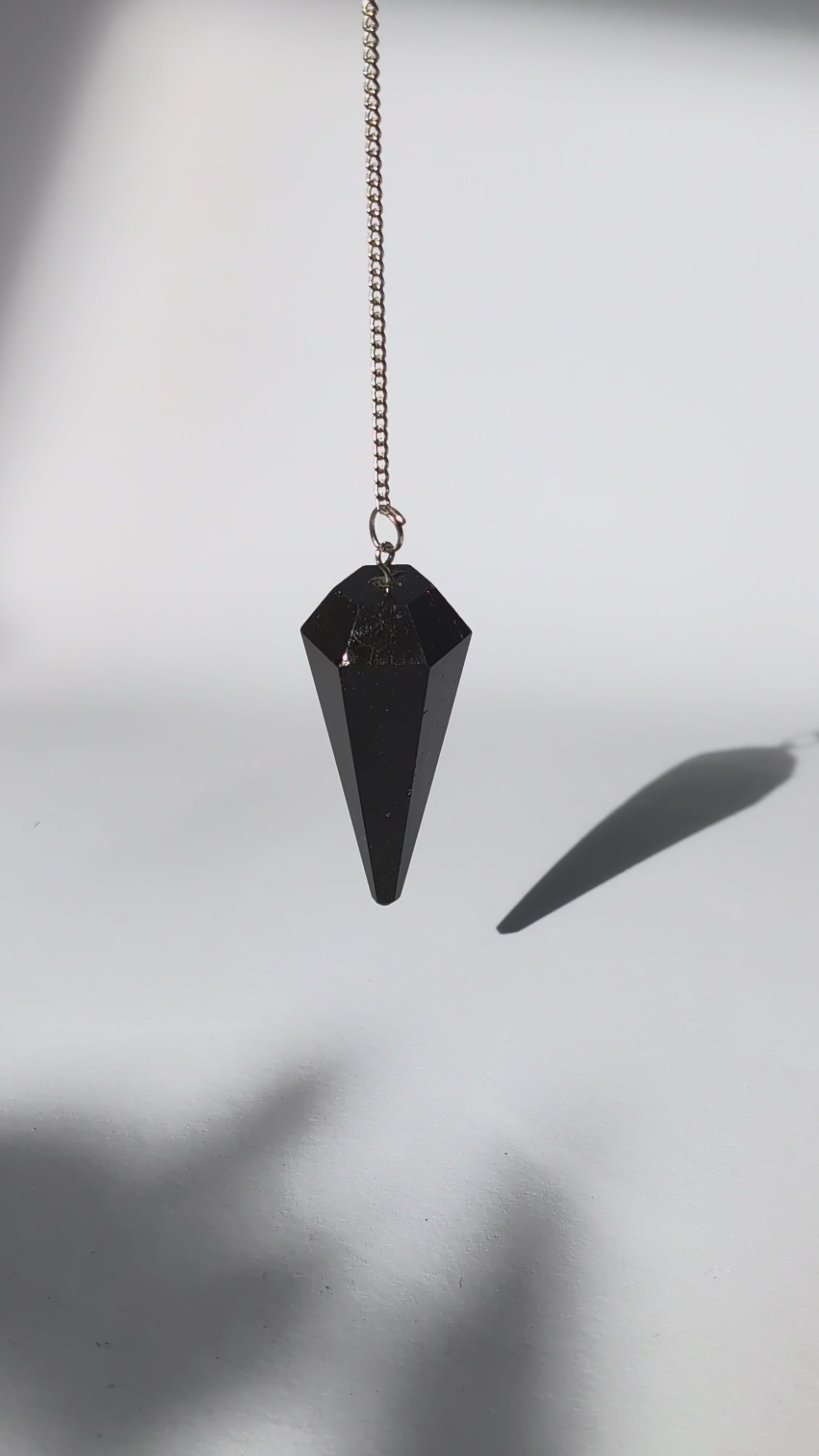 Schwarzes Turmalin Pendel mit facettierter Spitze und versilberter Kette.