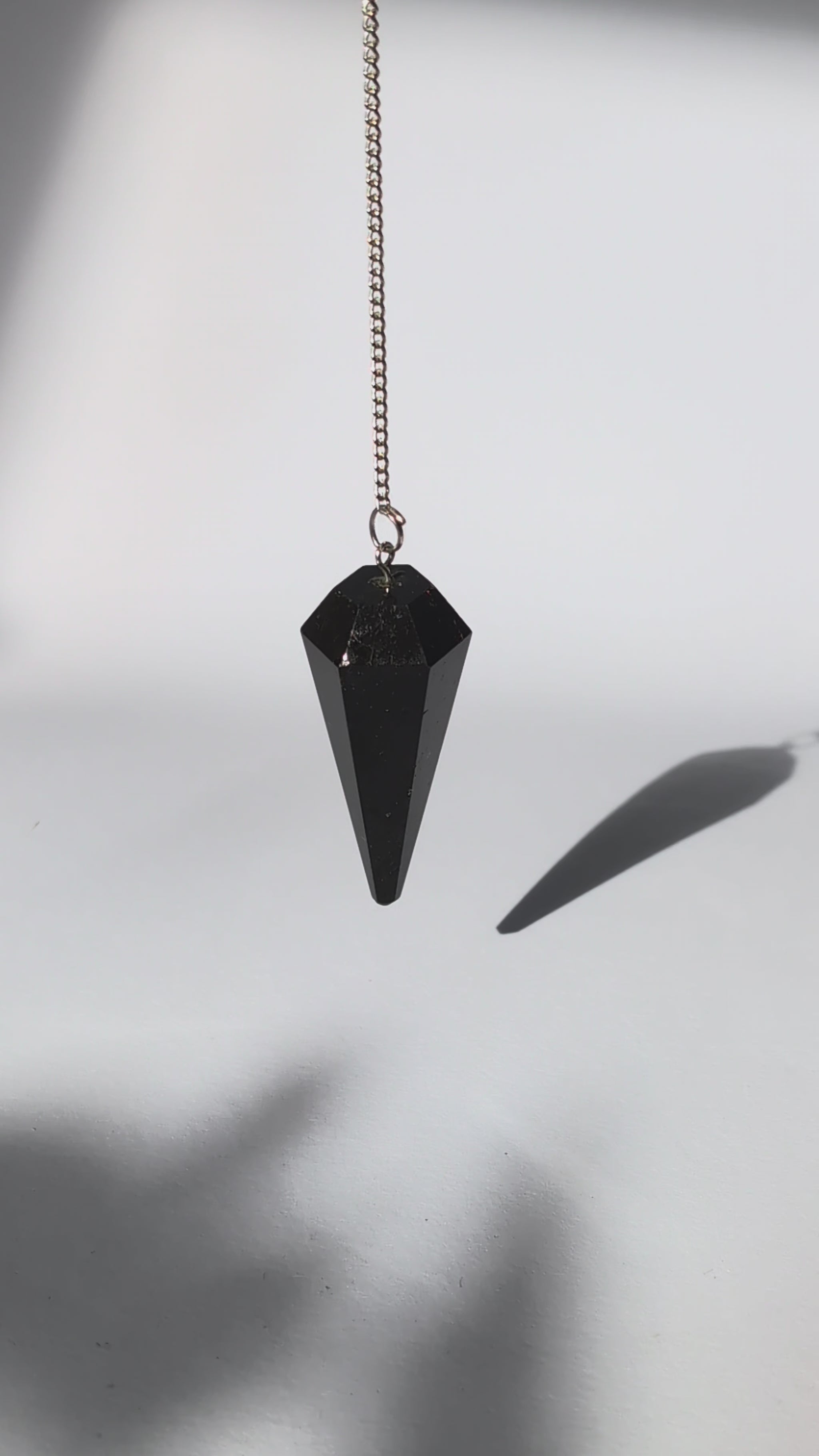 Schwarzes Turmalin Pendel mit facettierter Spitze und versilberter Kette.