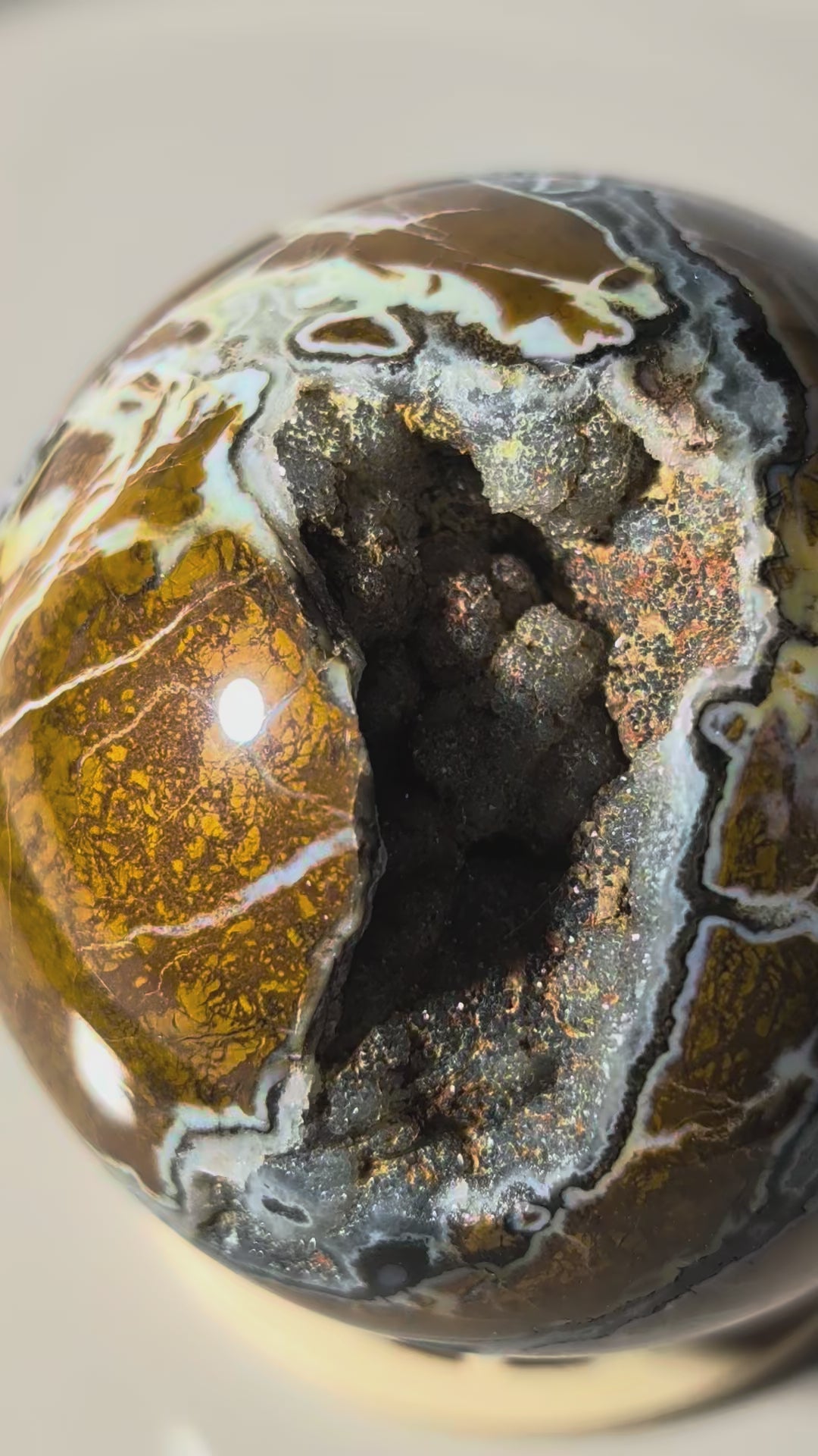 Polierte Drusenachat Kugel in Nahaufnahme mit offener Kristall-Geode und goldgelber Bänderung