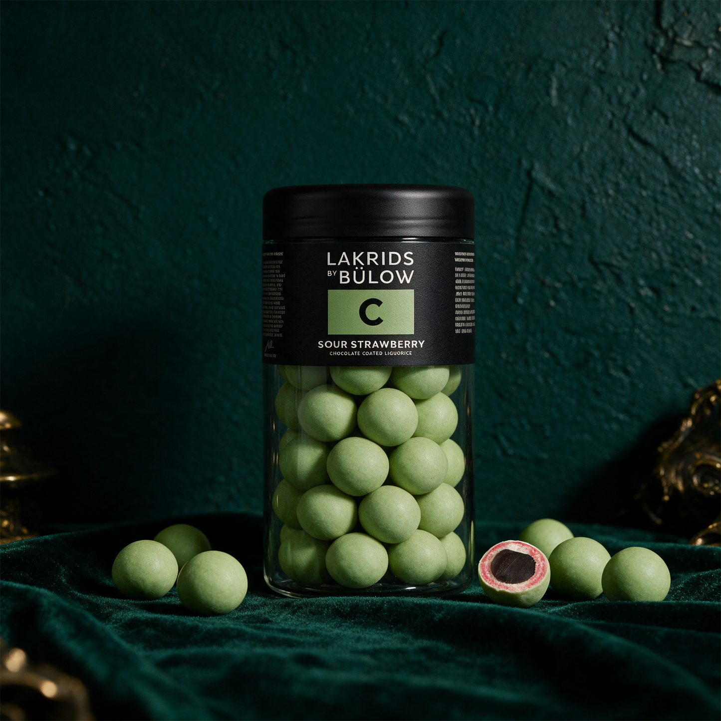 LAKRIDS by Bülow Sour Strawberry | Lakritz in weißer Schokolade – Anwendung vor tiefem Smaragdgrün