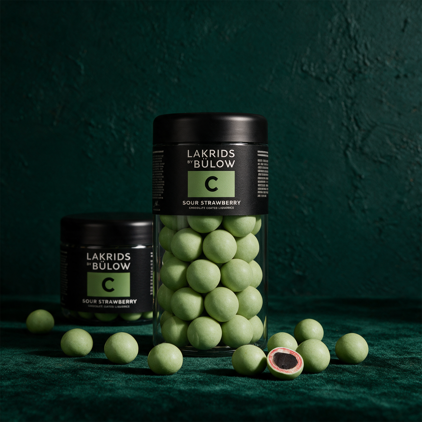 LAKRIDS by Bülow Sour Strawberry | Lakritz in weißer Schokolade – Produktansicht vor tiefem Smaragdgrün