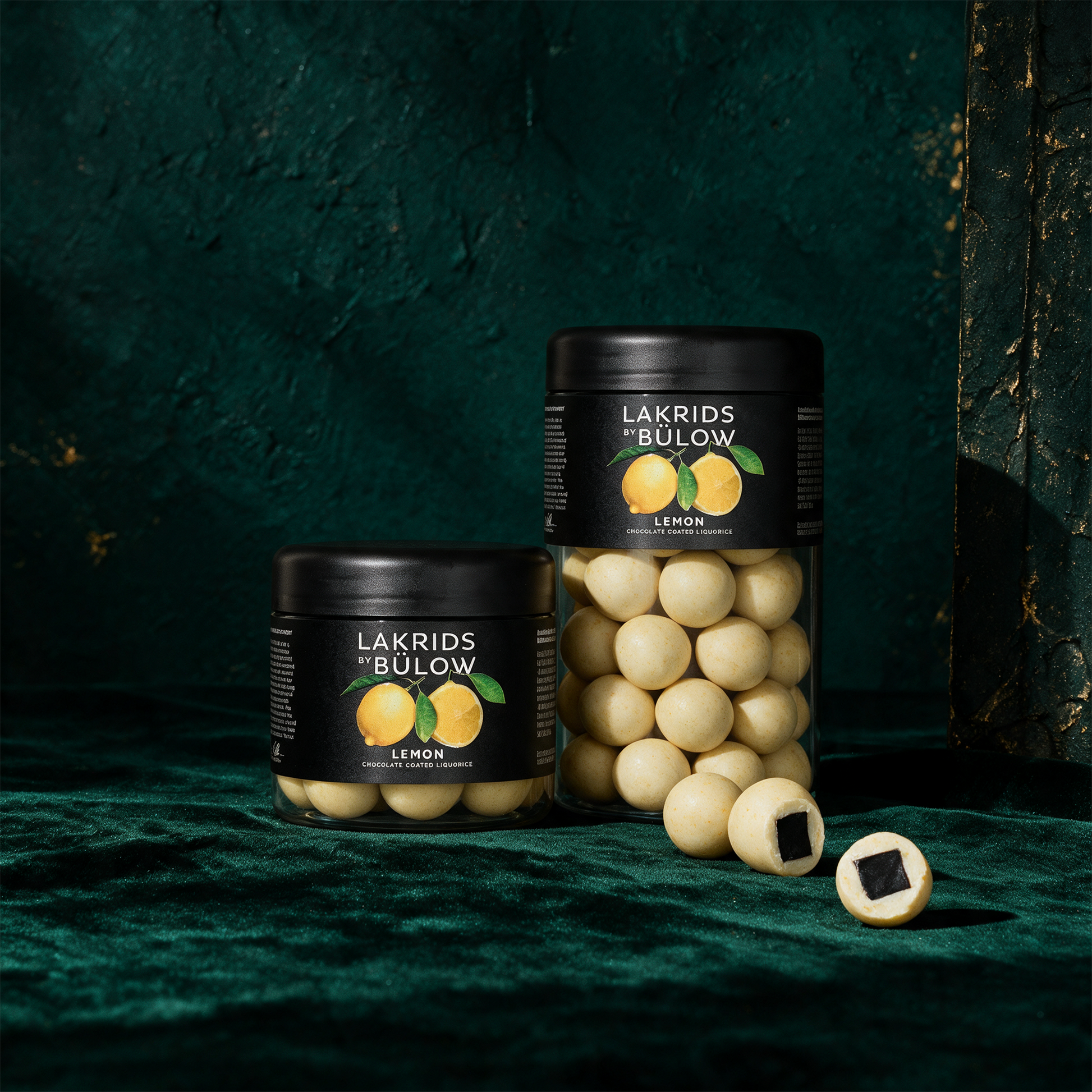 LAKRIDS by Bülow Læmon | Lakritz mit Zitrone & weißer Schokolade – Produktansicht vor tiefem Smaragdgrün