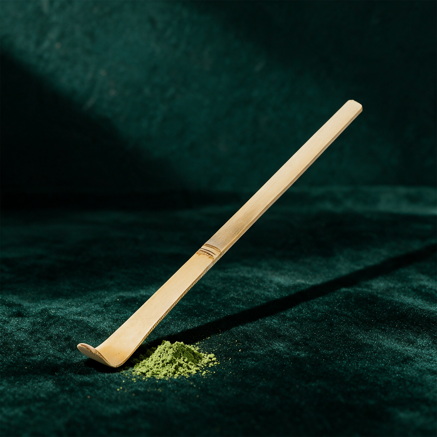 Matcha-Löffel Chashaku aus weißem Bambus vor tiefem Smaragdgrün