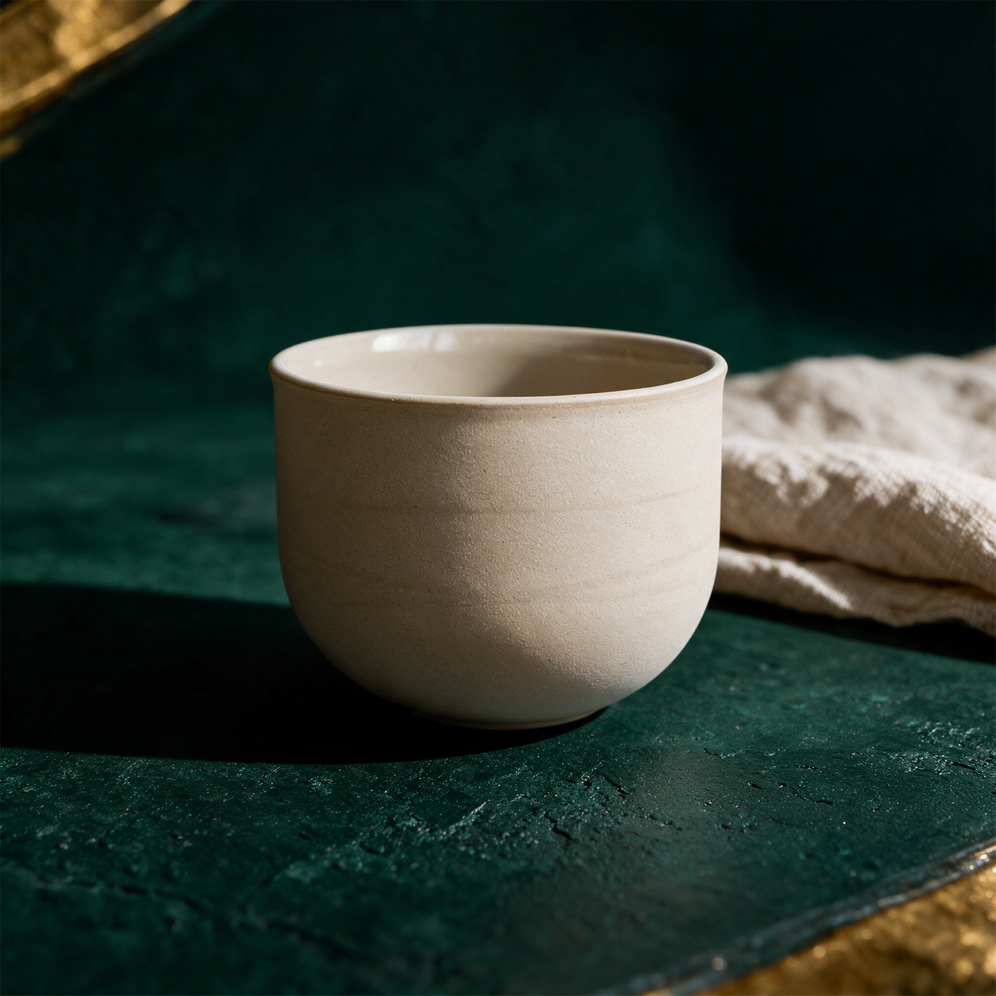 OCHA Teetasse beige – Produktansicht vor tiefem Smaragdgrün