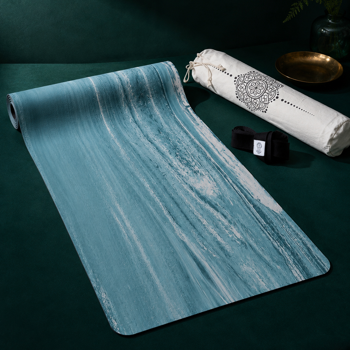 Yogamatte PURE von Divasya-Yoga auf dunkelgrünem Hintergrund mit schwarzem Gurt und weißer bedruckter Hülle