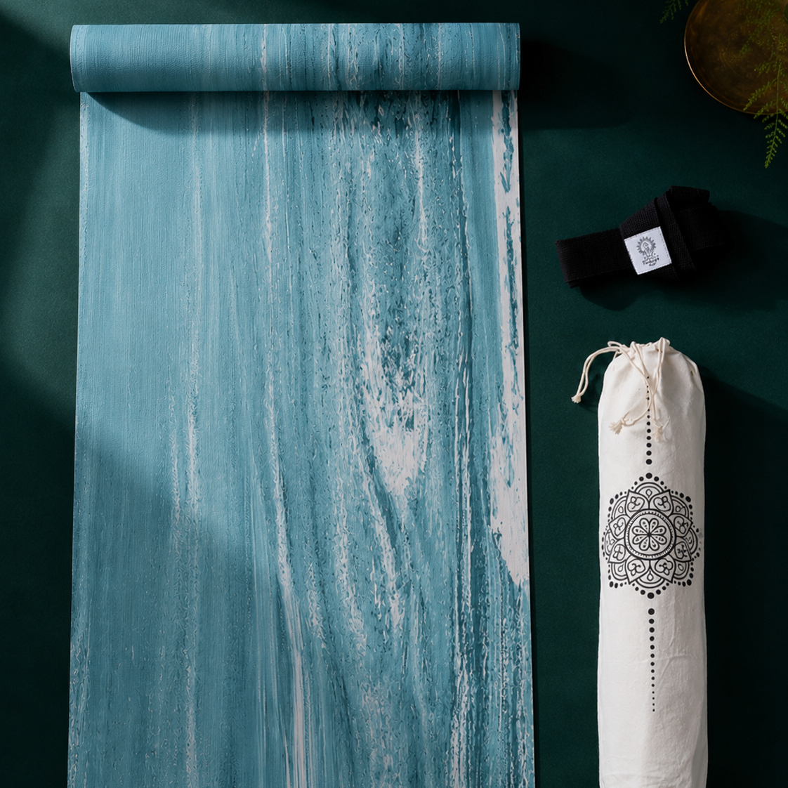 Yogamatte PURE von Divasya-Yoga als Flatlay auf dunkelgrünem Hintergrund mit schwarzem Gurt und weißer bedruckter Hülle